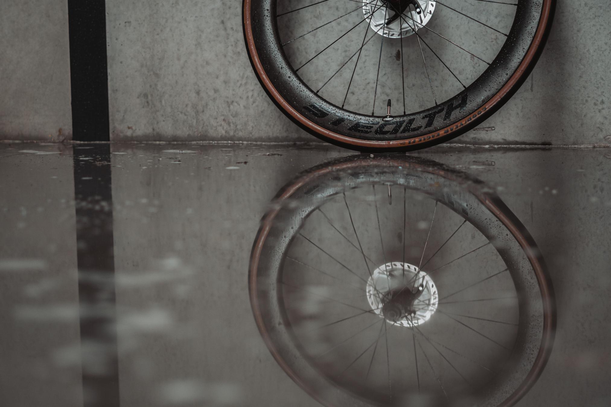 A wheel of a bike standing on wet ground.
